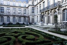 an elaborate garden in front of a large building with many windows and balconies