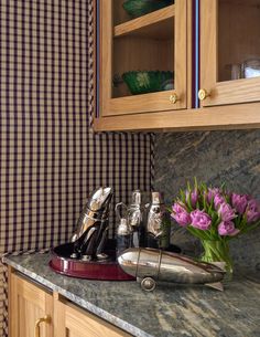 a kitchen counter topped with lots of clutter and purple tulips in a vase