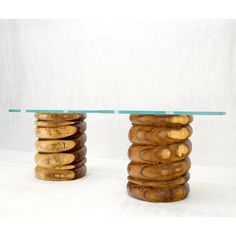 two tables made out of wood with glass top on each side and stacked wooden discs