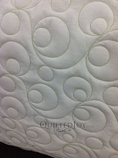 the quilted pillow is white and has swirls on it