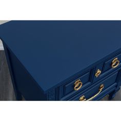 a blue desk with gold handles and drawers