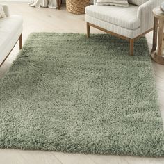 a living room with white furniture and a green rug on the floor in front of a chair