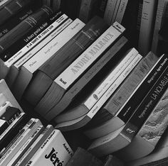 black and white photograph of books stacked on top of each other in a pile,