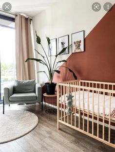 a baby's room with a crib, chair and potted plant