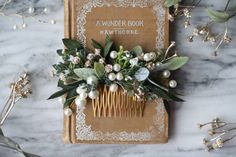 a book with flowers and greenery on top of it next to some hair combs