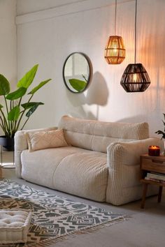 a living room filled with furniture next to a mirror and potted plant on the wall