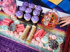 a table topped with cupcakes, cookies and candy