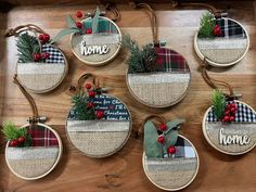 christmas ornaments are hanging on the wall with plaid and pine cones, evergreen branches, and red berries