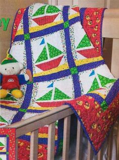 a baby crib with a quilted blanket and teddy bear on it's bed