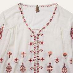 This top offers a soft and flowing silhouette with bohemian embroidered detailing throughout, including subtly hidden buttons at the front. A relaxed choice for brunch, a music festival, or wherever else the season takes you. 100% Viscose 3/4 Elastic Gathered Sleeves Curved Front and Straight Back Yokes Self-Covered Button Front Imported Bohemian V-neck Blouse With Embroidered Hem, Summer Embroidered V-neck Peasant Top, Bohemian 3/4 Sleeve Summer Blouse, Bohemian Blouse With 3/4 Sleeves For Summer, Summer Folk Style Blouse With Boho Print, Summer Folk Blouse With Boho Print, Summer Boho Print Folk Blouse, Bohemian Spring Tops With 3/4 Sleeves, Bohemian V-neck Rayon Peasant Top