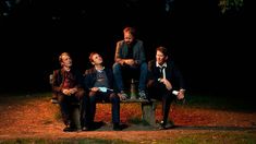 three men sitting on a bench in the dark