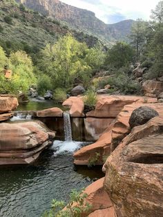 there is a small waterfall in the middle of some rocks and water flowing down it