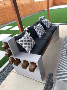 a couch sitting on top of a patio next to a wooden fence and green grass