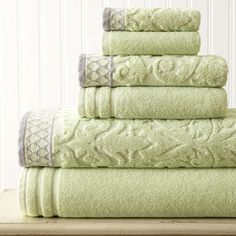 a stack of green towels sitting on top of a wooden table