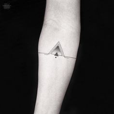 a black and white photo of a person's arm with a triangle tattoo on it