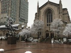 an old church with snow on the ground and people walking around in front of it