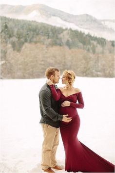 a pregnant couple standing in the snow together