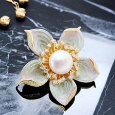 Introducing our exquisite Flower Brooch - a highly sought-after accessory crafted from premium Silver 925 and elegantly finished with a radiant 18k gold plating. This stunning brooch features a captivating design inspired by nature, with a natural pearl at its center, ensuring you stand out in style. Our Silver 925 Flower Brooch is not just jewelry; it's a fashionable masterpiece designed to complement your outfit effortlessly. The combination of top-quality materials, including the sought-after Luxury Flower Shaped Brooch Jewelry, Luxury Flower Brooch As Gift, Luxury Flower Brooches For Gift, Elegant Silver Enamel Pin, Elegant Gold Enamel Pin For Wedding, Elegant Silver Enamel Pin Gift, Elegant Flower Shaped Enamel Pin For Formal Occasions, Elegant Yellow Gold Enamel Pin Gift, Elegant Flower Shaped Brooches For Anniversary