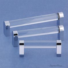 three clear acrylic tube holders on a blue surface with two silver metal handles