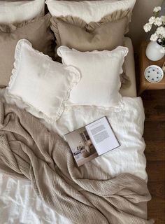 a bed with pillows and blankets on top of it next to a table with flowers