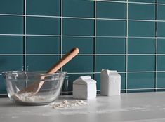 a wooden spoon sitting in a bowl on top of a counter next to a blue tiled wall