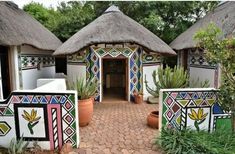 an outdoor area with potted plants and thatched roof huts on the side of it