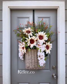 a basket filled with flowers sitting on top of a gray door frame next to a grey front door