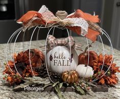 an arrangement of pumpkins and fall decorations in a wire basket with the words hello fall written on it