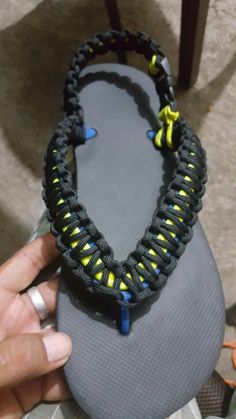 someone is holding up a pair of sandals with yellow and blue beads on them,