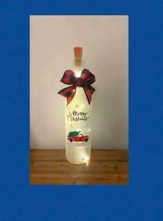 a bottle with a bow on it sitting on top of a wooden table next to a wall