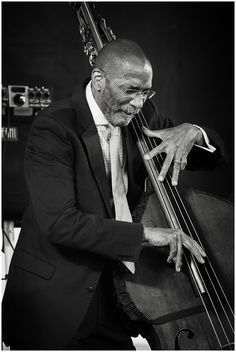 a black and white photo of a man in a suit playing the bassoons