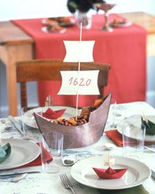 a table set with plates and napkins for a sailboat centerpiece on it