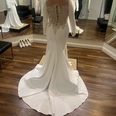 the back of a wedding dress is shown in front of a mirror and mannequins