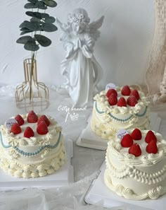 two cakes with white frosting and fresh strawberries on top are sitting next to each other