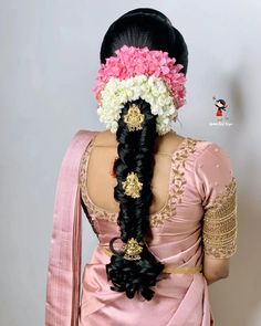 a woman with long black hair in a pink sari and flowered headpiece