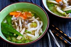 two bowls filled with soup and vegetables on top of a table