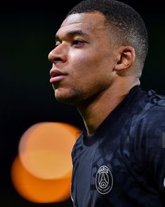 a close up of a soccer player wearing a black uniform and looking off to the side