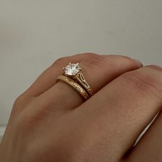 a woman's hand with a gold ring and a white diamond on her finger