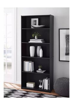 a black bookcase with four shelves in the middle and two vases on top