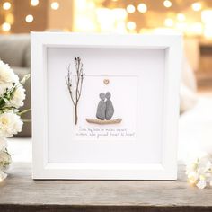 a white frame with a teddy bear sitting on top of it next to some flowers