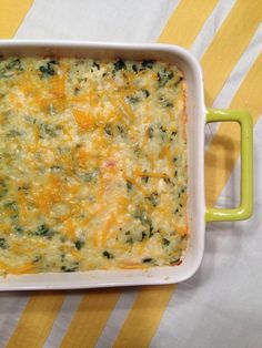 a casserole dish with cheese and spinach in it on a yellow and white striped tablecloth