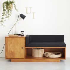 a black couch sitting on top of a wooden cabinet next to a lamp and potted plant