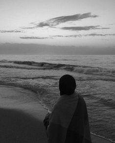 a person standing on the beach looking out at the water and waves in the ocean