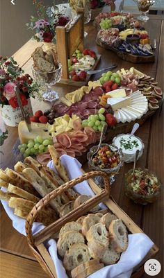 a wooden table topped with lots of different types of breads and fruit on top of it