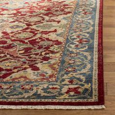 a red and blue rug with an ornate design on the bottom, sitting on a wooden floor