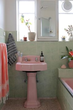 a pink sink sitting under a bathroom mirror next to a bath tub and window sill