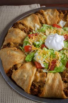 a taco pizza with lettuce, tomatoes and sour cream