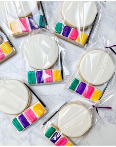 cookies decorated with colorful icing in plastic wrappers on a marble countertop, ready to be eaten