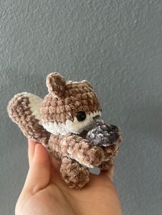 a hand holding a small brown and white stuffed animal