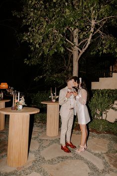 a man and woman kissing in front of a table with candles on it at night